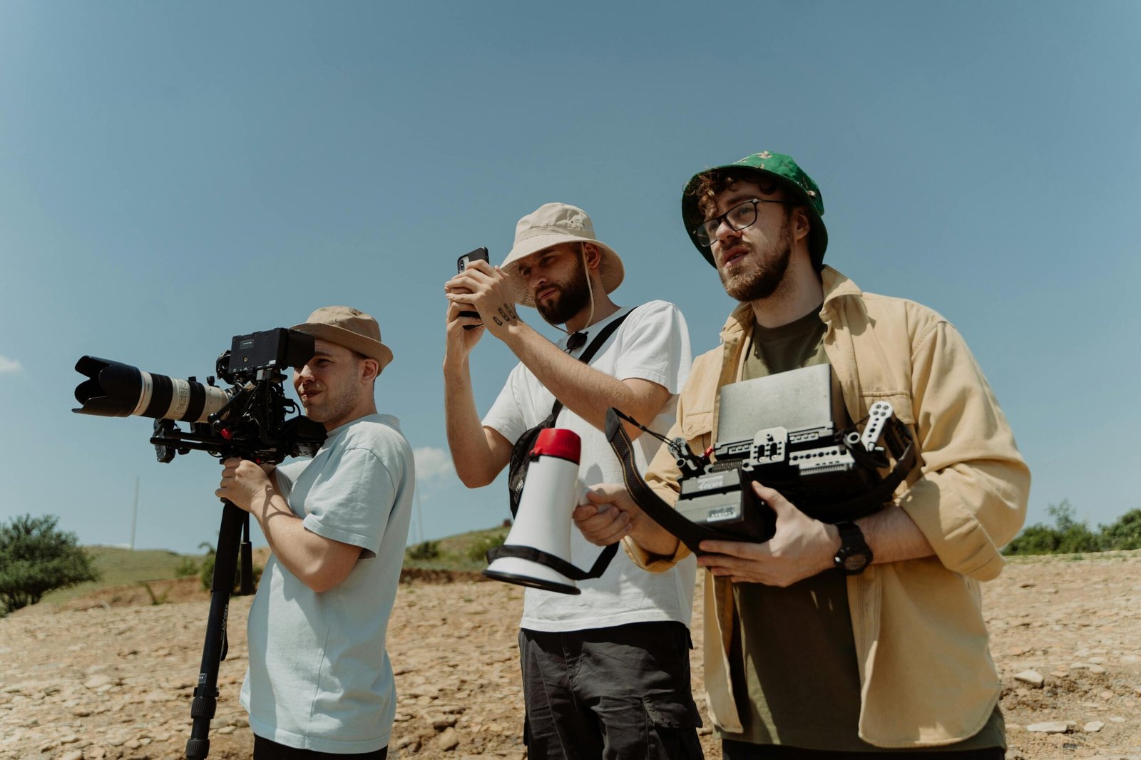 Three men with cameras and equipment shooting a film outdoors.